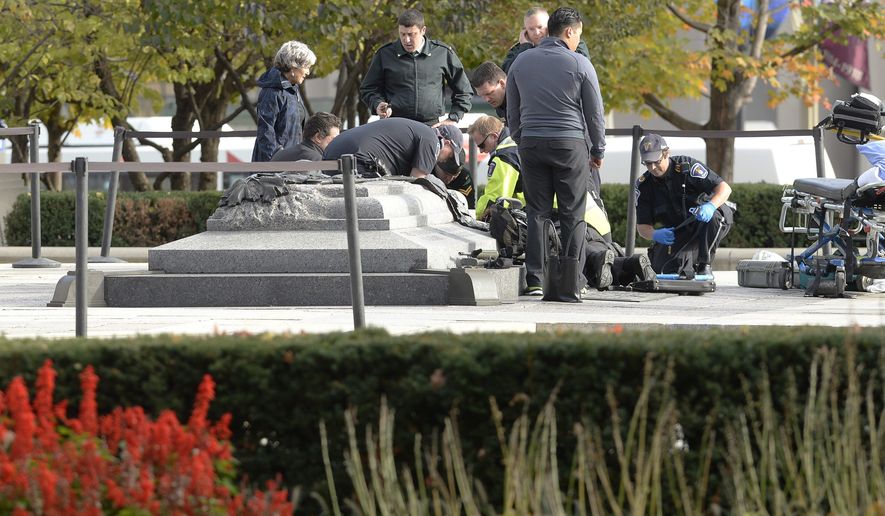Emergency personnel tend to a soldier shot at the National Memorial near Parliament Hill in Ottawa on Wednesday Oct. 22, 2014. The soldier standing guard at the National War Memorial was shot by an unknown gunman and people reported hearing gunfire inside the halls of Parliament. Prime Minister Stephen Harper was rushed away from Parliament Hill to an undisclosed location, according to officials. (AP Photo/The Canadian Press, Adrian Wyld)