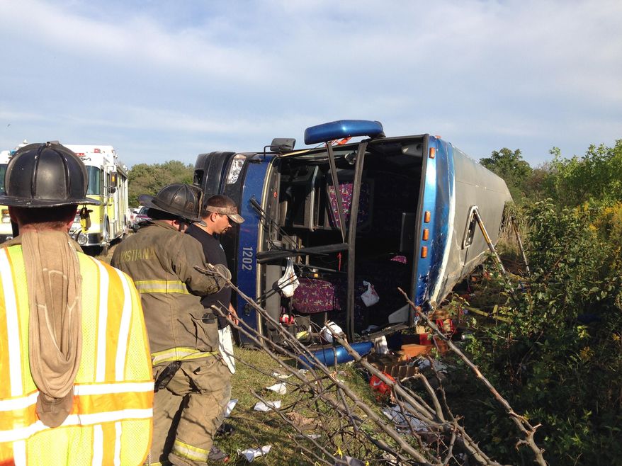 FILE - In this Sept. 21, 2014 file photo, passengers from a tour bus are treated for injuries near the overturned bus at the Tybouts Corner onramp from southbound Delaware 1 to Red Lion Road in Bear, Del. Recordings obtained by The Associated Press under the Freedom of Information Act indicate that 911 operators struggled to learn exactly where the crash occurred because passengers didn't know where they were. (AP Photo/The Wilmington News-Journal, John J. Jankowski, File)