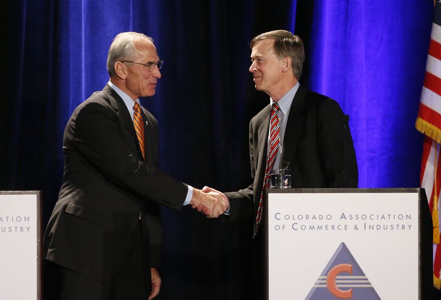 Colorado Gov. John Hickenlooper, right, shakes hands with his opponent, Republican candidate for governor Bob Beauprez, at the start of a debate in Denver, Thursday, Oct. 23, 2014. (AP Photo/Brennan Linsley)