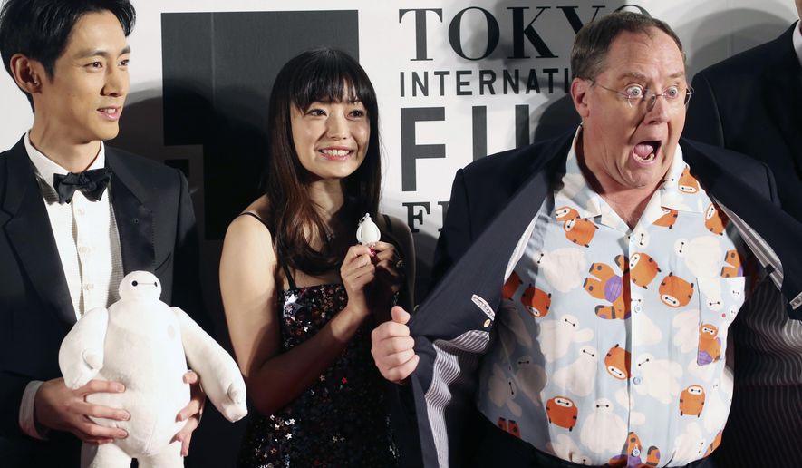FILE - In this Thursday, Oct. 23, 2014 file photo, John Lasetter, right, chief creative officer at Pixar, Walt Disney Aniamation Studios and Disney Toon Studios, poses for a photo with Japanese actors, Miho Kanno, center, and Kotaro Koizumi, both holding a character of "Baymax," the inflatable marshmallow-like robot in the animation movie "Big Hero 6," during an opening ceremony of the 27th Tokyo International Film Festival in Tokyo. Disney executives call their next film “a love letter to Japanese culture.” No wonder: This nation can’t get enough of animation, especially Disney’s. (AP Photo/Koji Sasahara, File)