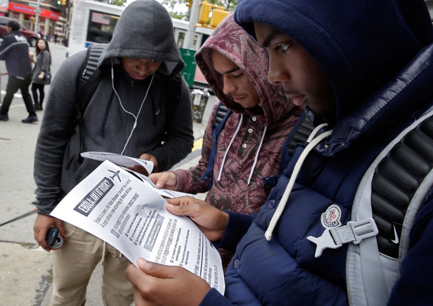 Mott Hall High School student Brian Binion, right, and fellow students read fliers about Ebola risk, near the apartment building of Ebola patient Dr. Craig Spencer, in New York, Friday, Oct. 24, 2014. Since there's no specific treatment, care is focused on easing symptoms to give the body enough time to fight off an infection, (AP Photo/Richard Drew)