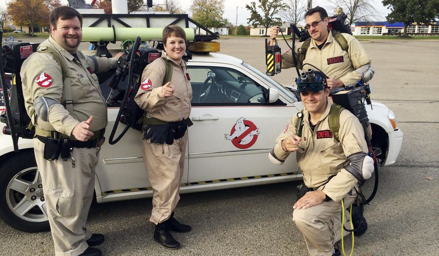 In this Oct. 20, 2014 photo, member of the Columbus Ghostbusters (from left): Jamie Knapp, Theresa Knapp, Brian Onofrio and Jeff Tatarek pose by their "Ekto Magnum" car in Columbus, Ohio. The group, impersonating characters from the 1984 movie, is one of several active in the state. (AP Photo/Columbus Dispatch, Kevin Joy)