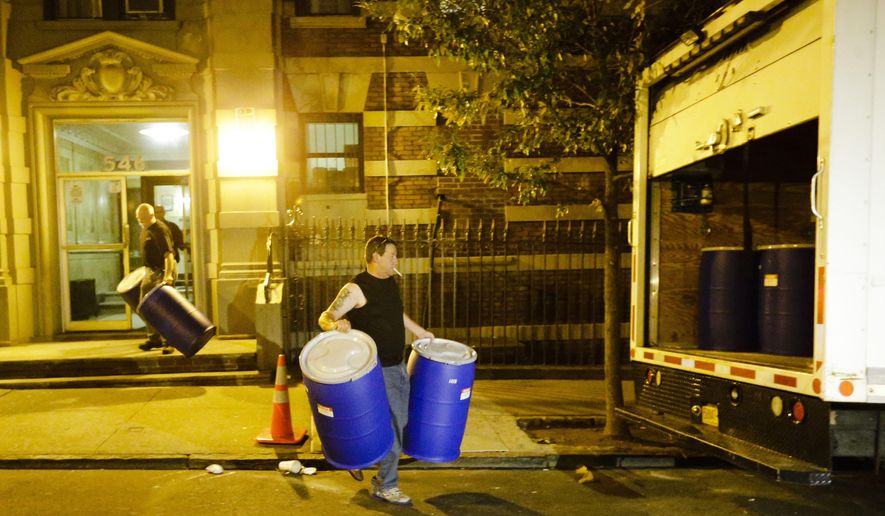 Workers from BioRecoveryCorp carry barrels from the apartment building of Ebola patient Dr. Craig Spencer Friday, Oct. 24, 2014, in New York. Spencer remained in stable condition while isolated in a hospital, talking by cellphone to his family and assisting disease detectives who are accounting for his every movement since arriving in New York from Guinea via Europe on Oct. 17. (AP Photo/Frank Franklin II)
