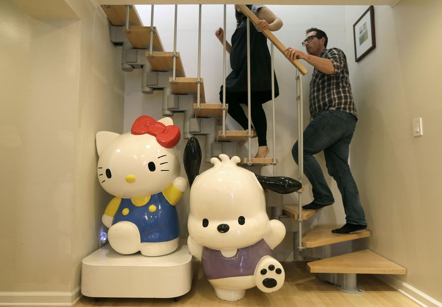 In this Monday, Oct. 13, 2014 photo, Salumeh Eslamieh, top left, and Marty Garrett walk up the stairs past statues of Sanrio characters Hello Kitty, bottom left, and Pochacco displayed at their home in San Francisco. The married couple turned the garage of their San Francisco home into a permanent showroom for their vast Hello Kitty collection. The couple met and bonded over the little white cat, and will be traveling to Los Angeles this week celebrate the character’s 40th birthday at Hello Kitty Con, opening Oct. 30, a four-day festival dedicated to all things Kitty. (AP Photo/Jeff Chiu)