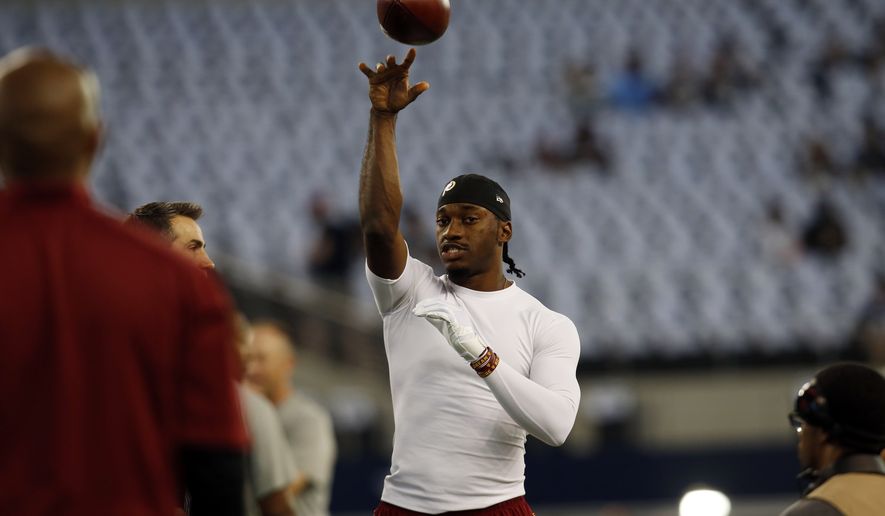 Washington Redskins quarterback Robert Griffin III (10) passes as he warms up before an NFL football game against the Dallas Cowboys, Monday, Oct. 27, 2014, in Arlington, Texas. (AP Photo/Tim Sharp) 
