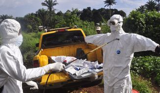 A health worker sprays disinfectant onto a college after they worked with the body of a man, suspected of contracting and dying form the Ebola virus on the outskirts of Monrovia, Liberia, Monday, Oct. 27, 2014. (AP Photo/Abbas Dulleh) ** FILE **