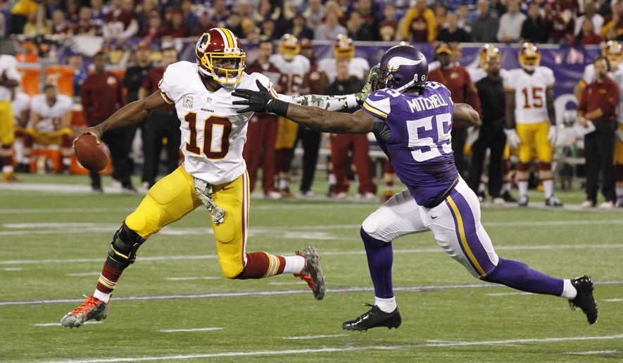 Washington Redskins quarterback Robert Griffin III, left, tries to break a tackle by Minnesota Vikings outside linebacker Marvin Mitchell during the first half of an NFL football game Thursday, Nov. 7, 2013, in Minneapolis. (AP Photo/Ann Heisenfelt)