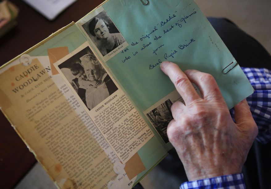 David Brink examines an inscription from his mother, Carol Ryrie Brink, in her book "Caddie Woodlawn" at his home in Minneapolis, Minn. Oct. 11, 2014. Brink said it was one of the first copies of "Caddie Woodlawn," which Carol penned based on her grandmother's life. (AP Photo/Minnesota Public Radio, )