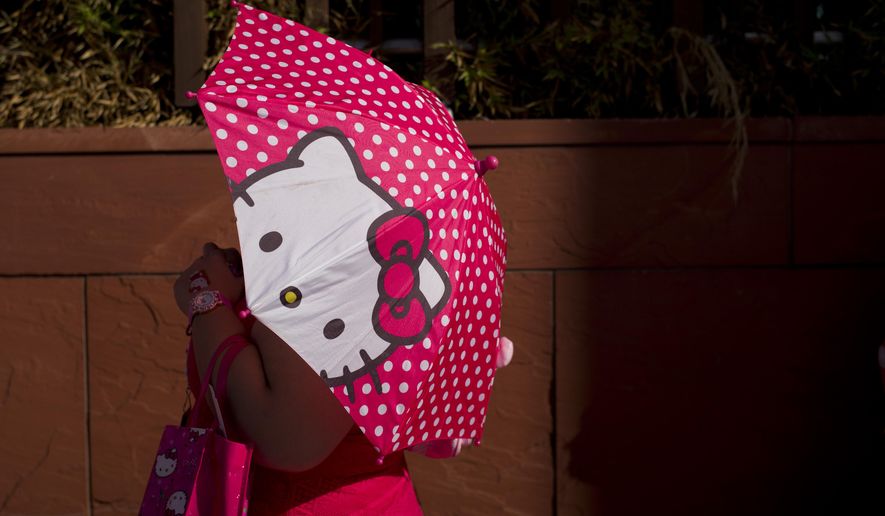 A woman uses a Hello Kitty umbrella to shelter from the sun while waiting in line for the Hello Kitty Con, the first-ever Hello Kitty fan convention, held at the Geffen Contemporary at MOCA Thursday, Oct. 30, 2014, in Los Angeles. The convention was held to honor the character's 40th birthday. (AP Photo/Jae C. Hong)