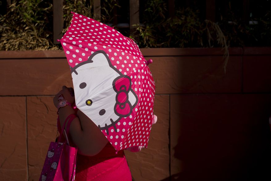 A woman uses a Hello Kitty umbrella to shelter from the sun while waiting in line for the Hello Kitty Con, the first-ever Hello Kitty fan convention, held at the Geffen Contemporary at MOCA Thursday, Oct. 30, 2014, in Los Angeles. The convention was held to honor the character's 40th birthday. (AP Photo/Jae C. Hong)