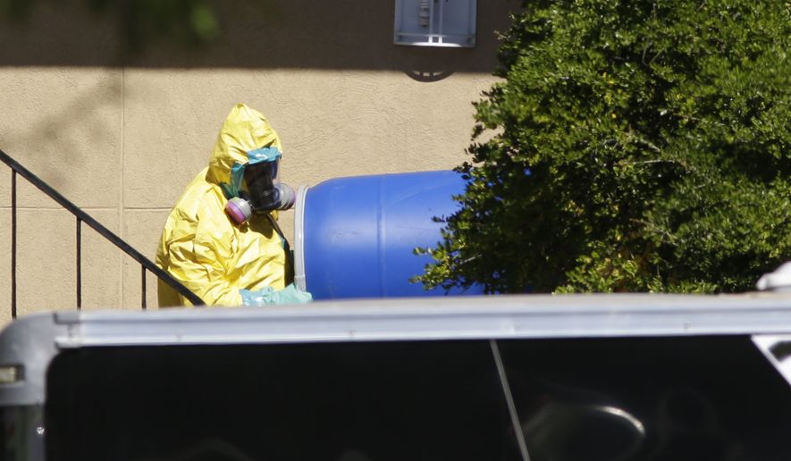 A hazardous material cleaner removes a blue barrel from the apartment in Dallas, where Thomas Eric Duncan, the Ebola patient who traveled from Liberia to Dallas stayed, in this Friday, Oct. 3, 2014, file photo. (AP Photo/LM Otero, File)
