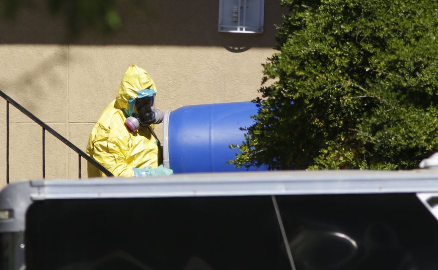 A hazardous material cleaner removes a blue barrel from the apartment in Dallas, where Thomas Eric Duncan, the Ebola patient who traveled from Liberia to Dallas stayed, in this Friday, Oct. 3, 2014, file photo. (AP Photo/LM Otero, File)