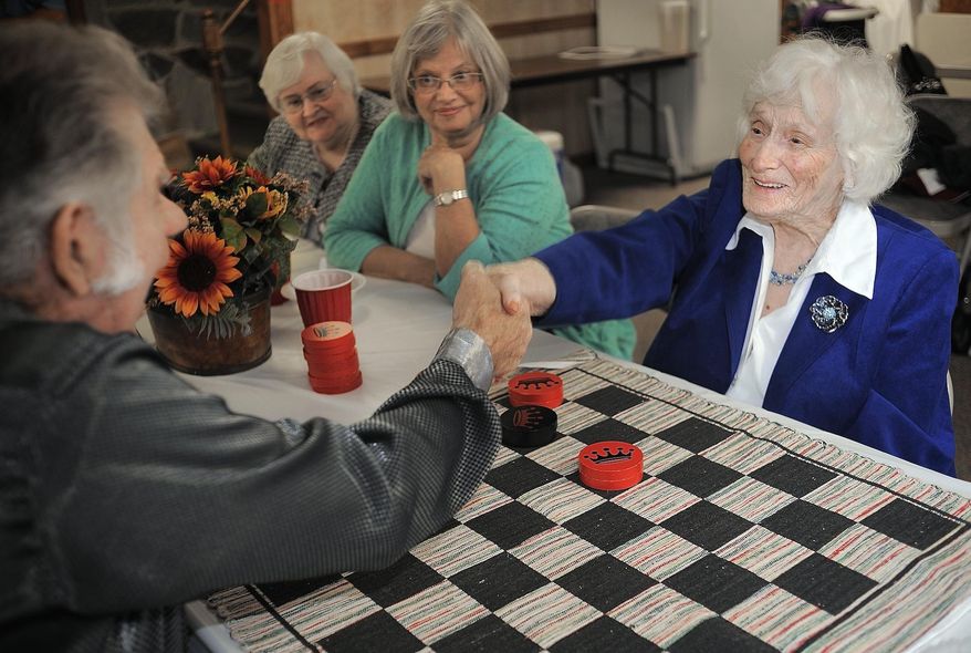 ADVANCE FOR SUNDAY NOV. 2 AND THEREAFTER - Phoebe Patton and Jim Austin shake hands after a competitive checkers game at Mount Carmel Baptist Church in Midland, Va. Phoebe Patton turned 100 years-old on Sept. 22, 2014. She is the checkers champion at church in Fauquier County. (AP Photo/The Free Lance-Star, Suzanne Carr Rossi)