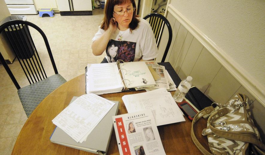 In this Oct. 21, 2014 photo, Stephanie Hanke, stepmother of missing teenager Brittney Wood, looks over materials related to the search for the youth at her home in Mobile, Ala. The teen hasn't been seen since May 2012 and is presumed dead, but 11 relatives and family friends have since been arrested as members of an alleged ring that swapped children for sex. Authorities said Wood could have been a key witness. (AP Photo/Jay Reeves)