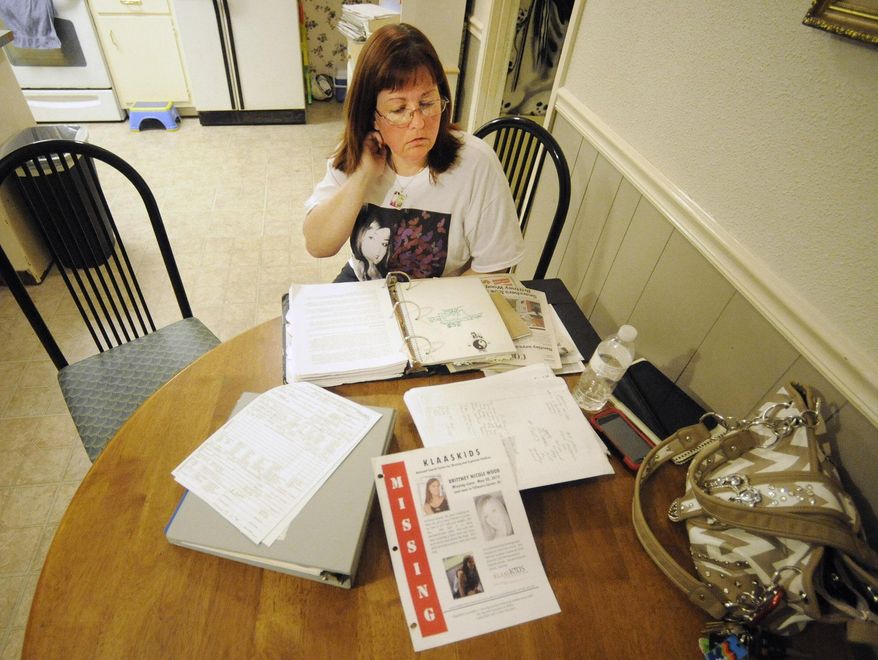 In this Oct. 21, 2014 photo, Stephanie Hanke, stepmother of missing teenager Brittney Wood, looks over materials related to the search for the youth at her home in Mobile, Ala. The teen hasn't been seen since May 2012 and is presumed dead, but 11 relatives and family friends have since been arrested as members of an alleged ring that swapped children for sex. Authorities said Wood could have been a key witness. (AP Photo/Jay Reeves)