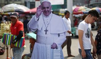 Filipinos pass by a cutout of Pope Francis during a gathering of relatives of missing left-wing activists in Manila, Philippines as they observe All Souls Day on Sunday, Nov. 2, 2014. The group said they are asking Pope Francis to intercede in seeking justice for their missing loved ones. Having no grave or cemetery to visit, the relatives gather each year, bearing candles and flowers, and demand that the government take steps to produce their loved ones, dead or alive. (AP Photo/Aaron Favila)