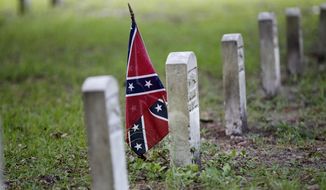 A confederate flag is seen at a tombstone on the cemetery at Beauvoir House, Jefferson Davis&#x27; historic home, in Biloxi, Miss., Thursday, Aug. 16, 2012. (AP Photo/Gerald Herbert)