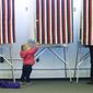 Zoe Buck, a 14-month-old child, checks out an empty voting booth as at her mother, Julie Buck, votes at left, Tuesday Nov. 4, 2014, at the Alaska Zoo polling place in Anchorage, Alaska. (AP Photo/Ted S. Warren)