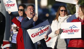 Cory Gardner, center, Republican candidate for the U.S. Senate seat in Colorado, joins supporters in waving placards on the corner of a major intersection in south Denver suburb of Centennial, Colo., early on Tuesday, Nov. 4, 2014. Gardner is facing Democratic incumbent U.S. Sen. Mark Udall in a pitched battle for the seat. (AP Photo/David Zalubowski)