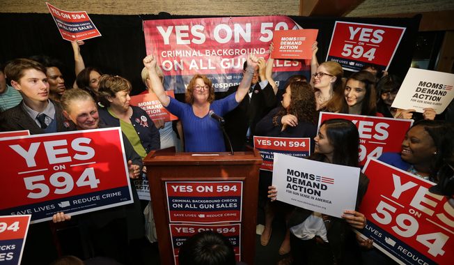 Cheryl Stumbo, center, raises her arms as she finishes speaking at an election night party for Initiative 594, a measure seeking universal background checks on gun sales and transfers, Tuesday, Nov. 4, 2014, in Seattle. Stumbo, the citizen sponsor of the initiative, is a survivor in the shooting at the Jewish Federation in Seattle in 2006. The initiative is one of two competing gun initiatives in Washington state. The other measure, Initiative 591, would prevent any such expansion of background checks. (AP Photo/Elaine Thompson)