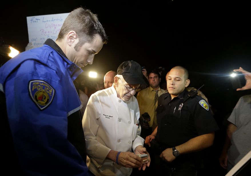 Homeless advocate Arnold Abbott, 90, of the nonprofit group Love Thy Neighbor Inc., center, gets his drivers license to hand to a Fort Lauderdale police officer, Wednesday, Nov. 5, 2014, in Fort Lauderdale, Fla. Abbott and a group of volunteers were feeding the homeless in a public parking lot next to the beach when he was issued a summons to appear in court for violating an ordinance that limits where charitable groups can feed the homeless on public property. Abbott w also recently arrested along with two pastors for feeding the homeless in a Fort Lauderdale park. (AP Photo/Lynne Sladky)