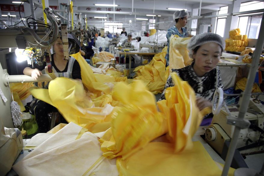 In this photo taken Thursday, Oct. 30, 2014, Chinese workers manufacture protection suits that meet the standards for use by healthcare workers treating Ebola patients at a factory of U.S. based Lakeland Industries in Anqiu city in eastern China's Shandong Province. Far from the Ebola hot zone, the sewing and gluing machines at a factory in China have been whirring more than usual to produce crucial yellow suits that protect the front-line medics more than 11,000 kilometers (7,000 miles) away in West Africa. (AP Photo/Wayne Zhang)