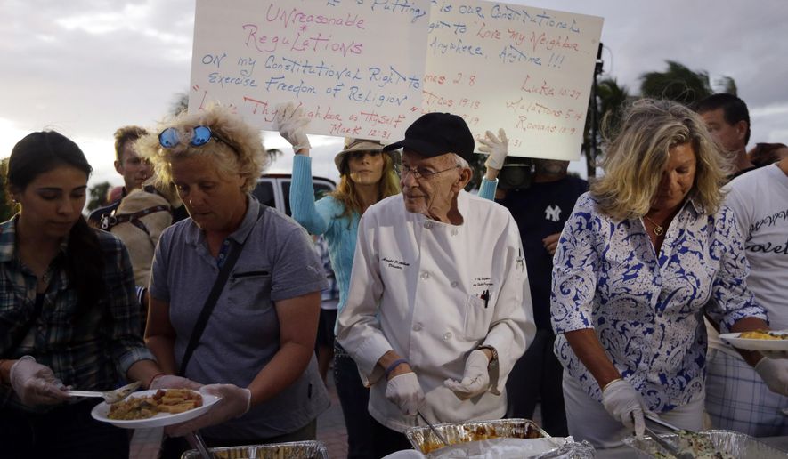 Homeless advocate Arnold Abbott, 90, director of the nonprofit group Love Thy Neighbor Inc., center, serves food to the homeless with the help of volunteers from a public parking lot next to the beach, Wednesday, Nov. 5, 2014, in Fort Lauderdale, Fla. Abbott was later issued a summons to appear in court for violating an ordinance that limits where charitable groups can feed the homeless on public property.  Abbott was also recently arrested along with two pastors for feeding the homeless in a Fort Lauderdale park. (AP Photo/Lynne Sladky)