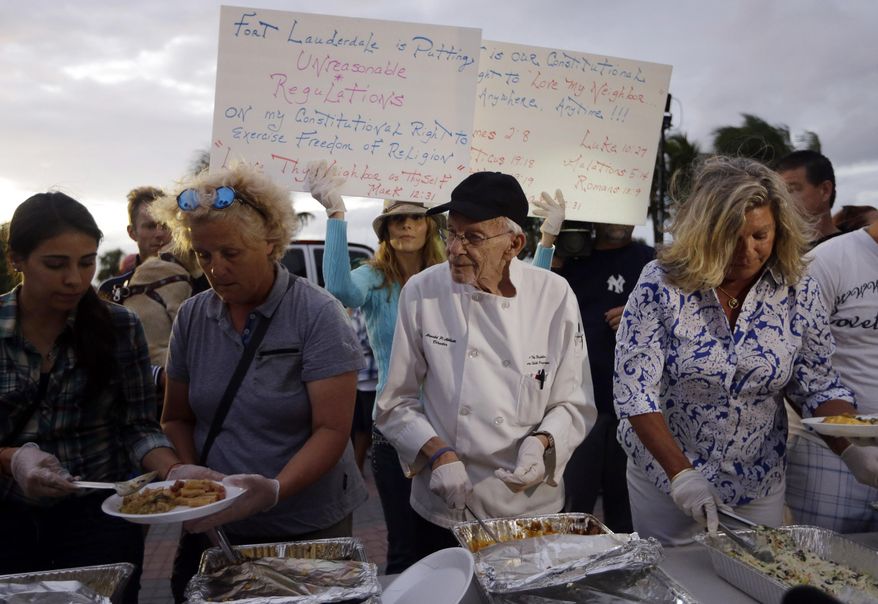 Homeless advocate Arnold Abbott, 90, director of the nonprofit group Love Thy Neighbor Inc., center, serves food to the homeless with the help of volunteers from a public parking lot next to the beach, Wednesday, Nov. 5, 2014, in Fort Lauderdale, Fla. Abbott was later issued a summons to appear in court for violating an ordinance that limits where charitable groups can feed the homeless on public property.  Abbott was also recently arrested along with two pastors for feeding the homeless in a Fort Lauderdale park. (AP Photo/Lynne Sladky)