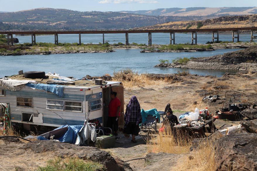 ADVANCE FOR USE SUNDAY, NOV. 9. 2014, AND THEREAFTER- This Aug. 22, 2014, photo shows the home of Ranetta Spino and her family at the river’s edge at Lone Pine, a Native American fishing site on the Columbia River near The Dalles, Ore. Lone Pine is one of 31 fishing sites developed as a replacement for tribal fishing grounds flooded or destroyed by hydroelectric dams. About 40 people, including children, permanently live at the fishing site in substandard conditions. (AP Photo/Gosia Wozniacka)