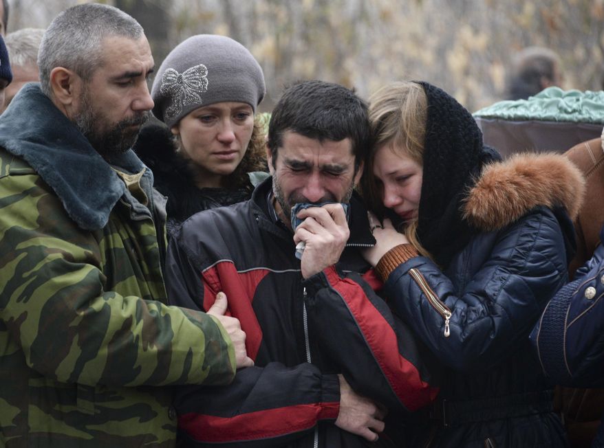 Relatives of 18-year-old Andrei Yeliseyev and 14-year-old Daniil Kuznetsov cry during a funeral at a local cemetery in Donetsk, eastern Ukraine, Friday, Nov. 7, 2014. The rebel stronghold of Donetsk on Friday mourned the two teenagers who were killed in Wednesday's artillery strike on a high school on the city's western outskirts. (AP Photo/Mstyslav Chernov)