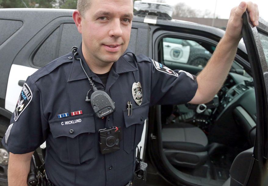 In this Nov. 5, 2014 photo, Sgt. Chris Wicklund of the Burnsville Police Department wears a body camera beneath his microphone. Minneapolis, with the largest police department in Minnesota, has become the latest to equip officers with body cameras in what officials say is an effort to improve transparency and hold police accountable. The goal in Burnsville is to have all uniformed offices equipped with cameras by the end of the year. (AP Photo/Jim Mone)