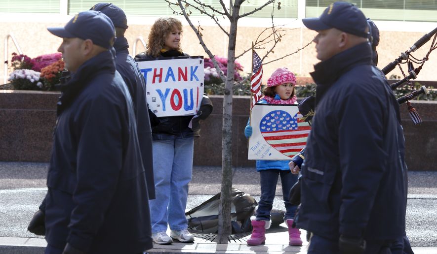 Sue Lippert, center left, and her 7-year-old granddaughter Ava Lippert, center right, hold signs thanking veterans as members of the U.S. Coast Guard march by in the Pittsburgh Veterans Day parade on Saturday, Nov. 8, 2014, in Pittsburgh. Lippert said Ava&#39;s mother is currently serving in the Air Force. The city moved their parade to Saturday ahead of the Nov. 11 holiday honoring veterans so more people could attend. (AP Photo/Keith Srakocic)