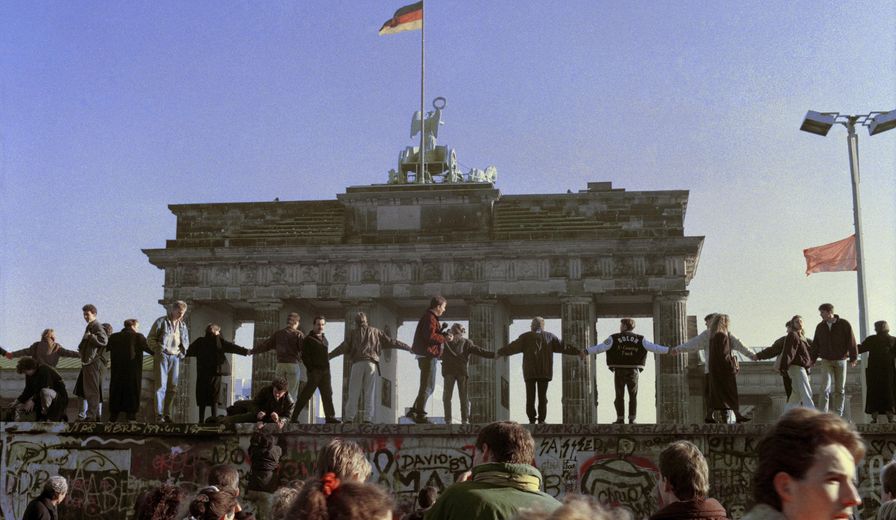 FILE - In this Nov. 10, 1989 file photo Berliners sing and dance on top of The Berlin Wall to celebrate the opening of East-West German borders. Thousands of East German citizens moved into the West after East German authorities opened all border crossing points to the West. In the background is the Brandenburg Gate. (AP Photo/Thomas Kienzle)