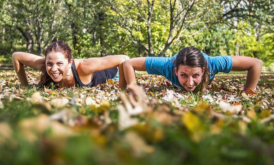 In this Oct. 7, 2014 photo, Katie Arnold, left, of Crystal Lake, Ill., and Samantha Laufer of Harvard. Ill. do push-ups while exercising at Veterans Acres Park in Crystal Lake. Starting in November, the two will travel to all 50 states in a year to practice Crossfit and hold fundraising events that will benefit different causes, including Crossfit for Hope, and to spread the message of health, wellness, and fitness. (AP Photo/Northwest Herald, Kyle Grillot) MANDATORY CREDIT