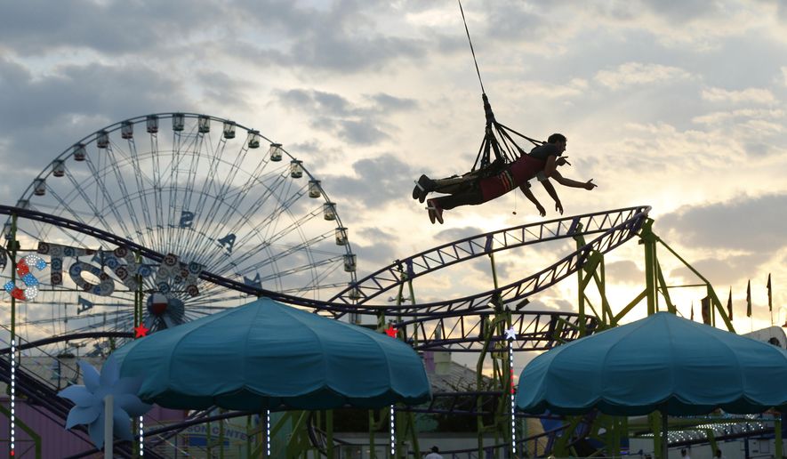 FILE - In this Friday, Sept. 26, 2014 file photo, Jeffrey Moore and Luis Hernandez fly through the air harnessed in the Skycoaster in the Midway on opening day of the State Fair of Texas in Fair Park in Dallas, Texas. Officials are hoping to privatize Fair Park using a model that has helped the Dallas Zoo. Since the zoo was spun off from city control and its management handed over to a private board, it has broken attendance records and been better maintained, with new programs and exhibits, The Dallas Morning News reported. (AP Photo/The Dallas Morning News, Nathan Hunsinger, File)