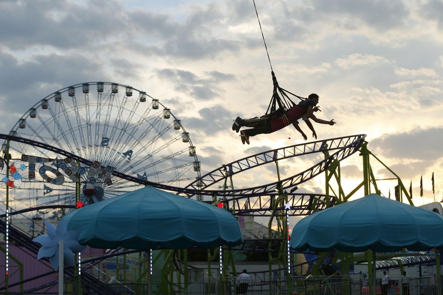 FILE - In this Friday, Sept. 26, 2014 file photo, Jeffrey Moore and Luis Hernandez fly through the air harnessed in the Skycoaster in the Midway on opening day of the State Fair of Texas in Fair Park in Dallas, Texas. Officials are hoping to privatize Fair Park using a model that has helped the Dallas Zoo. Since the zoo was spun off from city control and its management handed over to a private board, it has broken attendance records and been better maintained, with new programs and exhibits, The Dallas Morning News reported. (AP Photo/The Dallas Morning News, Nathan Hunsinger, File)