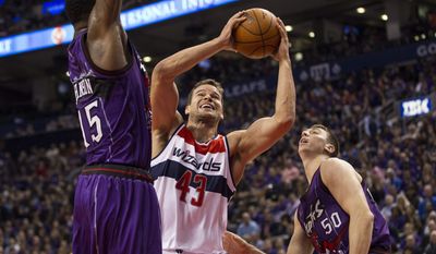 Washington Wizards&#39; Kris Humphries, center, shoots on Toronto Raptors&#39; Patrick Patterson, left, and Tyler Hansbrough during the first half of an NBA basketball game Friday, Nov. 7, 2014, in Toronto. (AP Photo/The Canadian Press, Chris Young)