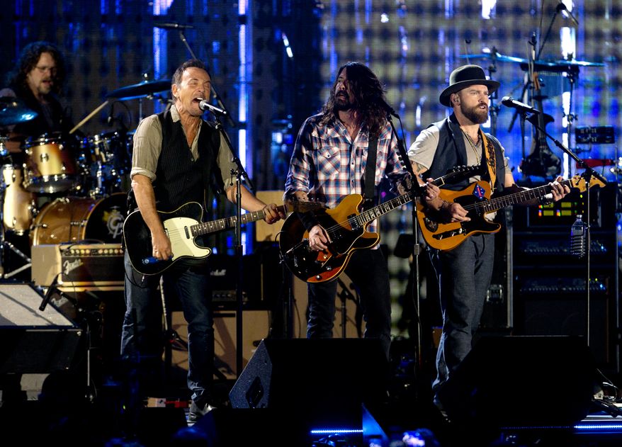 From left, Bruce Springsteen, Dave Grohl, and Zac Brown, sing on the National Mall in Washington, Tuesday, Nov. 11, 2014, during the Concert for Valor. The Veterans Day event is hosted by HBO, Starbucks and Chase and is free and open to the public. (AP Photo/Carolyn Kaster)