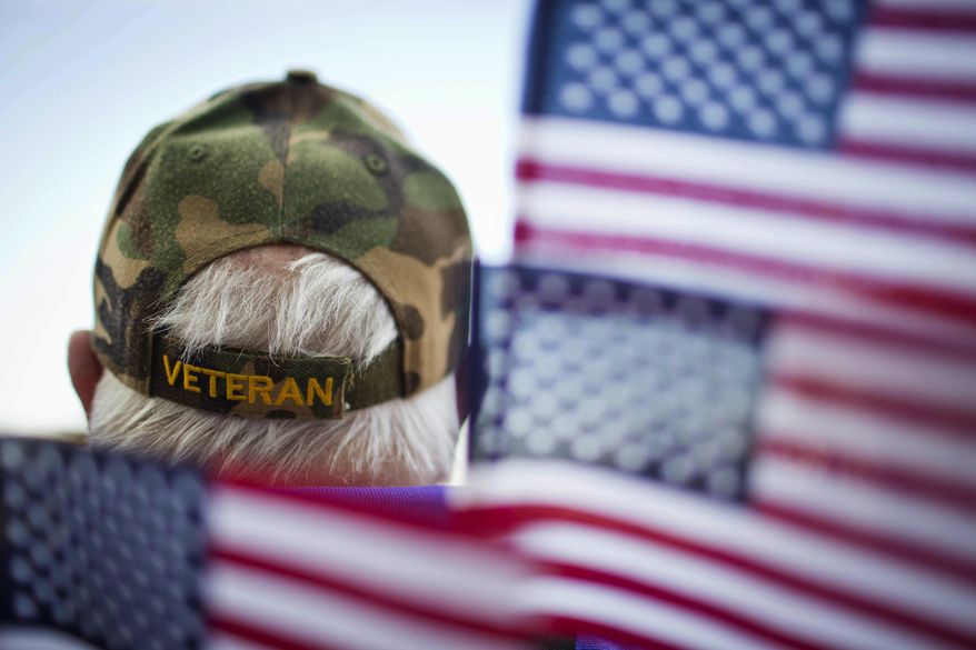Frank Lindsey wears a veterans hat surrounded by flags as he attends a Veterans Day parade Tuesday, Nov. 11, 2014, in Montgomery, Ala. (AP Photo/Brynn Anderson) ** FILE **