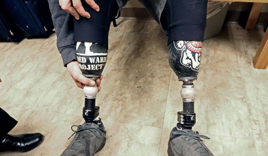 In this Monday, Nov. 10, 2014 photo, U. S. Marine Corps veteran Jake Janes positions one of his two prosthetic legs during an appointment to have one of the limbs repaired at Prosthetic Laboratories in Monona, Wisc. Janes, a Marine from Evansville, Wisc. who lost both legs below the knee in Afghanistan, goes hunting and fishing with his artificial legs. Improved prosthetics are helping Wisconsin veterans who lost limbs during tours in the Middle East maintain active lifestyles. (AP Photo/Wisconsin State Journal, John Hart)