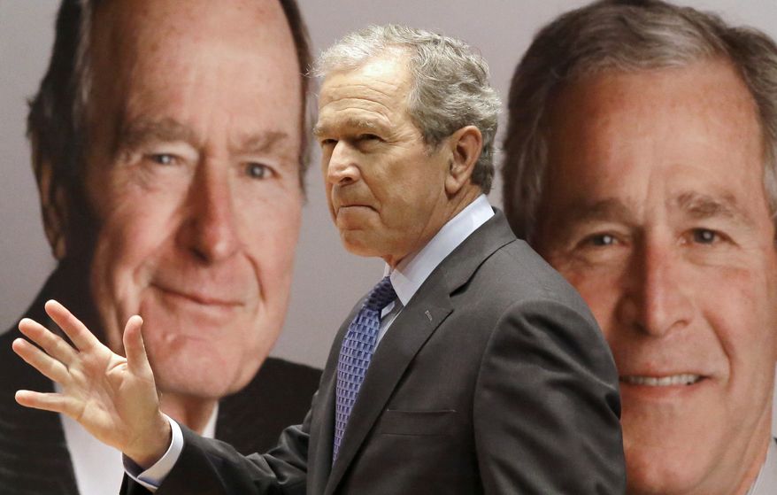Former President George W. Bush passes by a portrait of himself and his father former President George H.W. Bush as he takes the stage to discuss his new book, "41: A Portrait of My Father" at the his father's presidential library Tuesday, Nov. 11, 2014, in College Station, Texas. (AP Photo/Pat Sullivan)