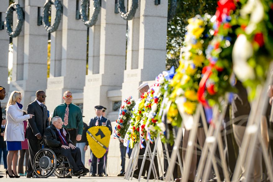 Retired Air Force Staff Sgt. Frank Rigo of Phoenix, Ariz., third from left, watches as a memorial wreath is placed at the World War II Memorial during a Veterans Day commemoration on the morning of Veterans Day, Washington, D.C., Tuesday, November 11, 2014. The event was hosted by the Friends of the World War II Memorial, the National Park Service and the Military District of Washington host. (Andrew Harnik/The Washington Times)