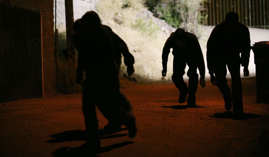 Four people sneak away from the US/Mexico border fence behind them after illegally crossing into the border town of Nogales, Arizona, on May 31, 2010. (Associated Press/Krista Kennell/Sipa Press) **FILE**
