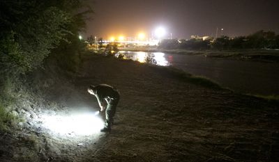In this Wednesday, July 23, 2014 photo, a U.S. Border Patrol agent looks at fresh footprints as he searches the banks of the Rio Grande River in Roma, Texas for a person who crossed the river from Ciudad Miguel Aleman, Tamaulipas, Mexico. (AP Photo/Austin American-Statesman, Jay Janner)