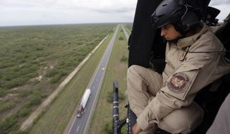 An U.S. Customs and Border Protection Air and Marine agent peers out of the open door of a helicopter during a patrol flight over McAllen, Texas, near the U.S.-Mexico border. (Associated Press)