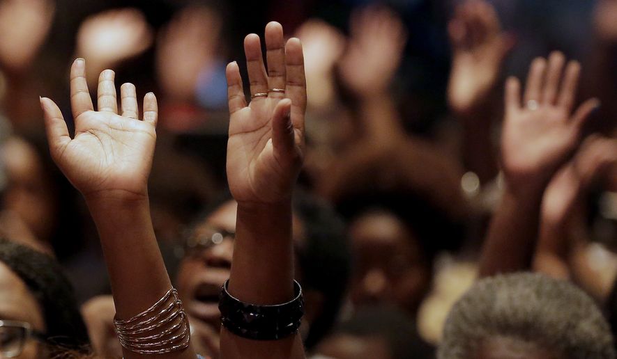 In this Aug. 17, 2014 file photo, people raise their hands during a rally at Greater Grace Church for Michael Brown, who was killed by police, last Saturday in Ferguson, Mo. (AP Photo/Charlie Riedel, File) ** FILE **