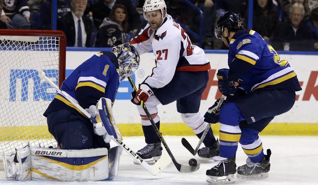 Washington Capitals&#x27; Karl Alzner, center, reaches for a puck as St. Louis Blues goalie Brian Elliott, left, and Kevin Shattenkirk defend during the first period of an NHL hockey game Saturday, Nov. 15, 2014, in St. Louis. (AP Photo/Jeff Roberson) 