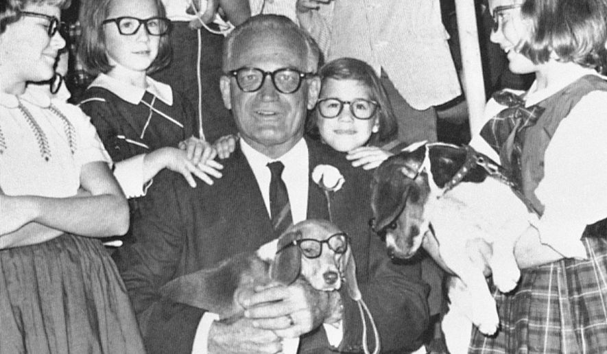 Youngsters in signature Goldwater glasses carry beagles to greet Sen. Barry Goldwater during a campaign stop in Montgomery, Alabama. (associated press)