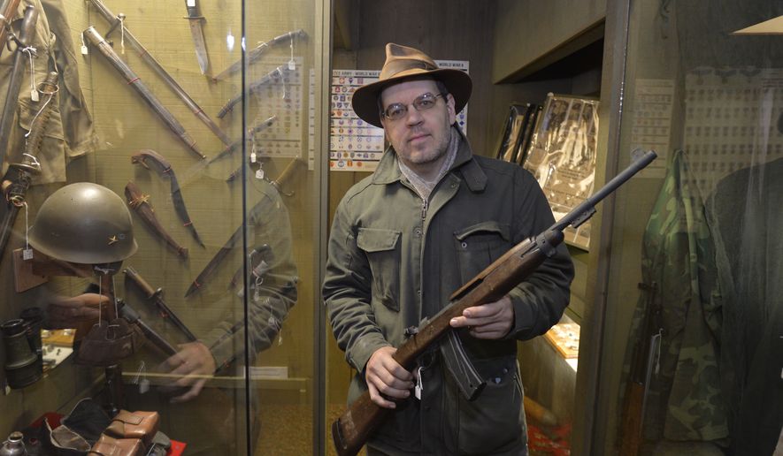 In this photo taken on Tuesday, Nov. 18, 2014, Lynden Museum director and curator Troy Loginbill, holds a Korean War M1  on loan to the Lynden, Wash., museum. The museum has decided to return the M1 carbine and ten other loaned weapons to their owners to comply with the new gun registration law Initiative 594. (AP Photo/The Bellingham Herald, Philip A. Dwyer)