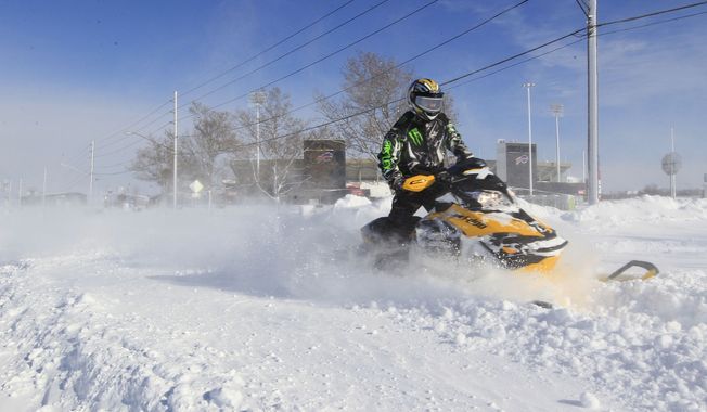 A snowmobiler makes his way down Abbott Road in front of Ralph Wilson Stadium,  home of the Buffalo Bills,  in Orchard Park, N.Y. on  Wednesday, Nov. 19, 2014.  A ferocious lake-effect storm left the Buffalo area buried under 6 feet of snow Wednesday, trapping people on highways and in homes, and another storm expected to drop 2 to 3 feet more was on its way. (AP Photo/The Buffalo News, Harry Scull Jr.)  TV OUT; MAGS OUT; MANDATORY CREDIT; BATAVIA DAILY NEWS OUT; DUNKIRK OBSERVER OUT; JAMESTOWN POST-JOURNAL OUT; LOCKPORT UNION-SUN JOURNAL OUT; NIAGARA GAZETTE OUT; OLEAN TIMES-HERALD OUT; SALAMANCA PRESS OUT; TONAWANDA NEWS OUT   